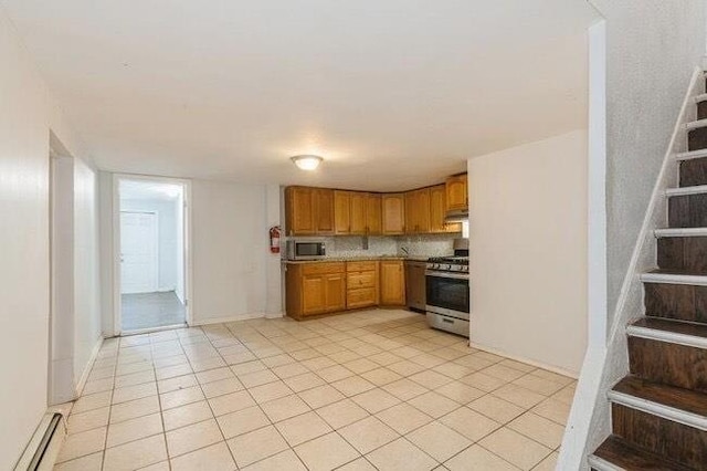 kitchen with brown cabinetry, light countertops, under cabinet range hood, light tile patterned floors, and stainless steel appliances