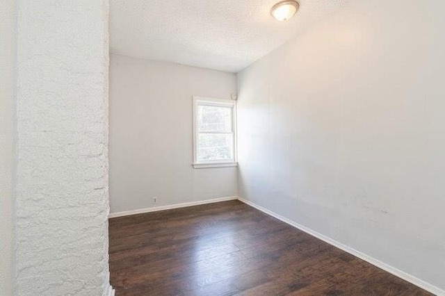 empty room featuring baseboards, a textured ceiling, and wood finished floors