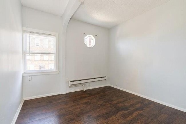 empty room featuring a baseboard radiator, wood finished floors, and a healthy amount of sunlight