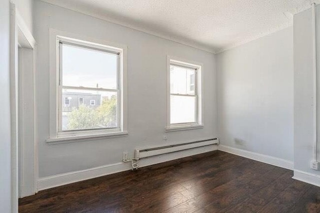 spare room with baseboards, baseboard heating, dark wood-type flooring, and a wealth of natural light