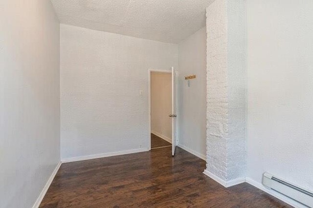 unfurnished room featuring baseboards, a baseboard radiator, and wood finished floors
