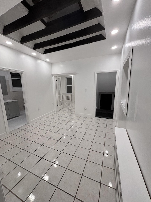 unfurnished living room featuring beam ceiling and light tile patterned floors