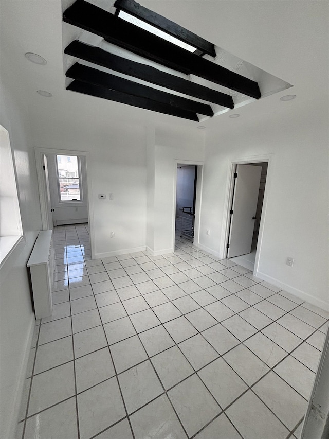 tiled empty room featuring beamed ceiling