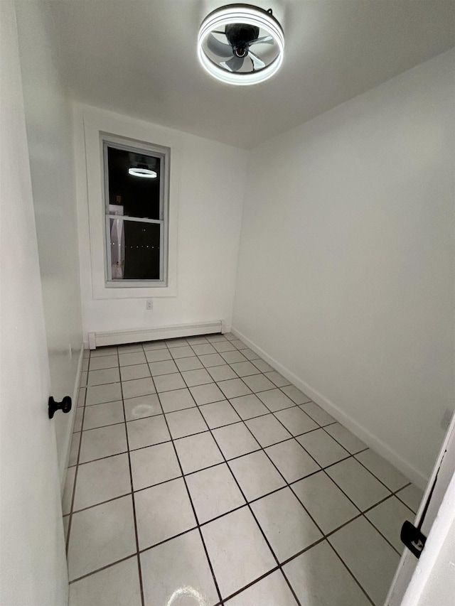 empty room featuring light tile patterned floors and a baseboard heating unit