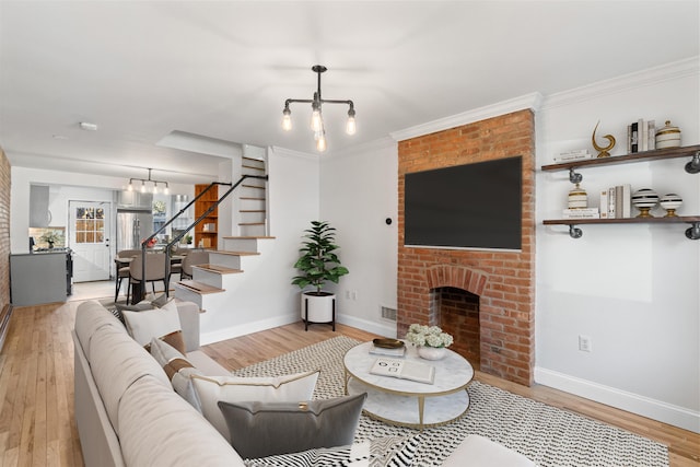 living area with a fireplace, wood finished floors, baseboards, stairway, and an inviting chandelier