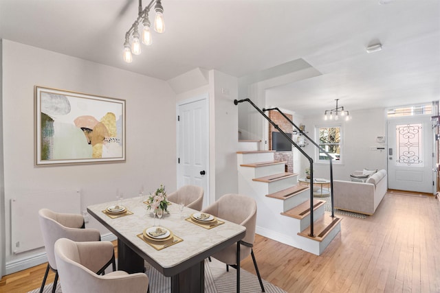 dining room with light wood finished floors, baseboards, stairway, and a chandelier