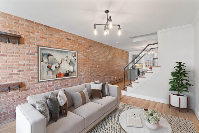 living room featuring baseboards, stairway, brick wall, and wood finished floors