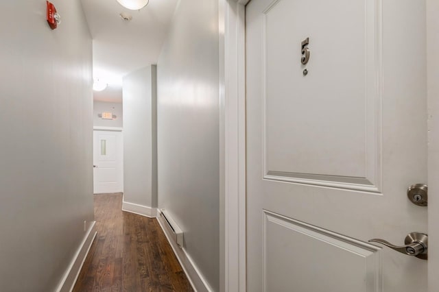 hall featuring dark wood-type flooring, a baseboard radiator, and baseboards