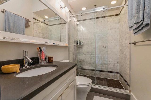 bathroom featuring toilet, a stall shower, and vanity