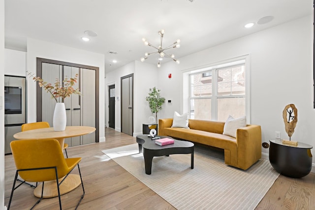 living area with recessed lighting, light wood-type flooring, and a notable chandelier