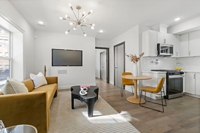 living room with light wood-style floors, recessed lighting, baseboards, and an inviting chandelier