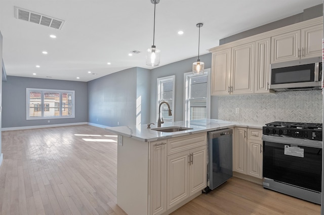 95 Claremont Ave, Jersey City, NJ 07304 - kitchen featuring appliances with stainless steel finishes, tasteful backsplash, light stone counters, light wood-style floors, and hanging light fixtures