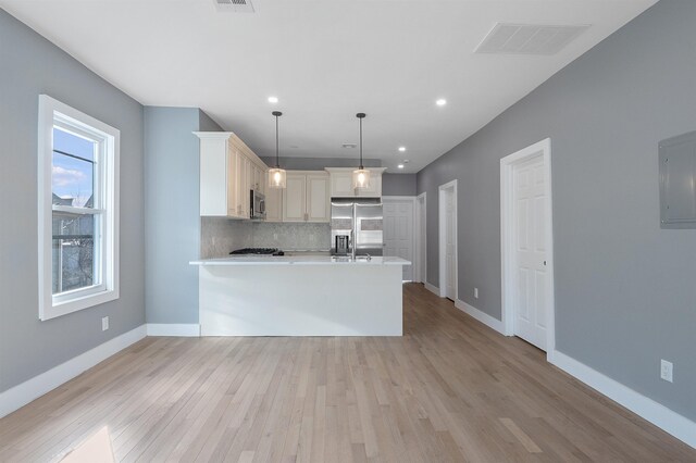 95 Claremont Ave, Jersey City, NJ 07304 - kitchen featuring appliances with stainless steel finishes, decorative backsplash, light wood-style flooring, electric panel, and a peninsula