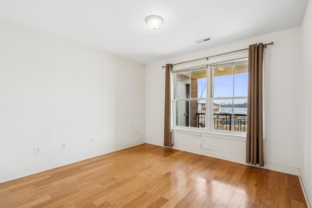 unfurnished room with baseboards, visible vents, and light wood-style floors