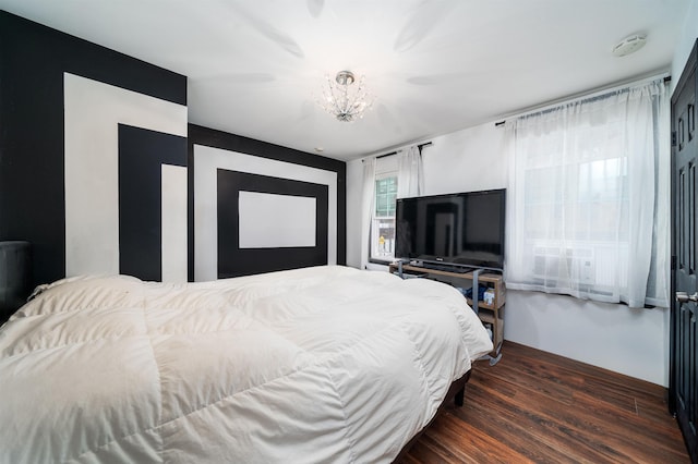 bedroom with wood finished floors and a notable chandelier