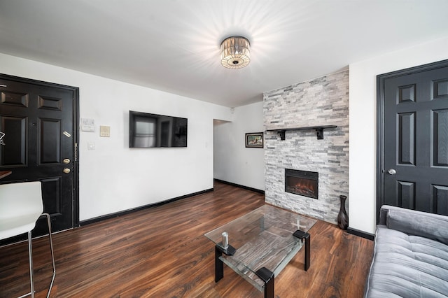 living room featuring a stone fireplace, wood finished floors, and baseboards