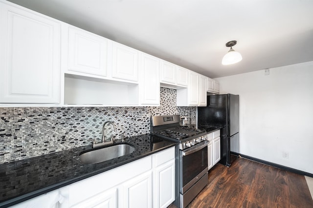 kitchen with backsplash, stainless steel range with gas cooktop, freestanding refrigerator, dark wood finished floors, and a sink