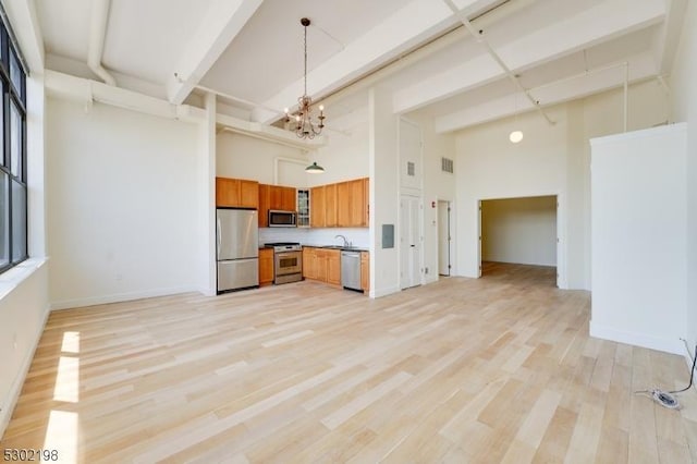 kitchen featuring an inviting chandelier, stainless steel appliances, a high ceiling, light hardwood / wood-style flooring, and sink