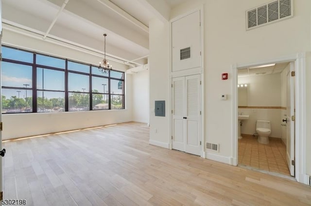 unfurnished living room with a notable chandelier and light hardwood / wood-style floors