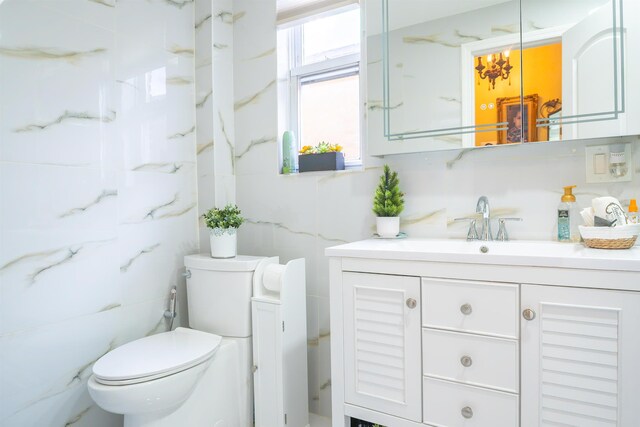 bathroom with toilet, tile walls, and vanity