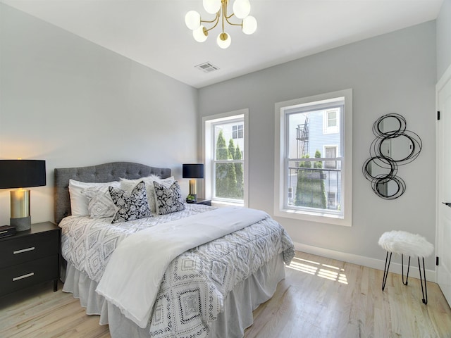 bedroom with light hardwood / wood-style flooring and a notable chandelier