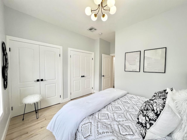 bedroom with light hardwood / wood-style floors and an inviting chandelier