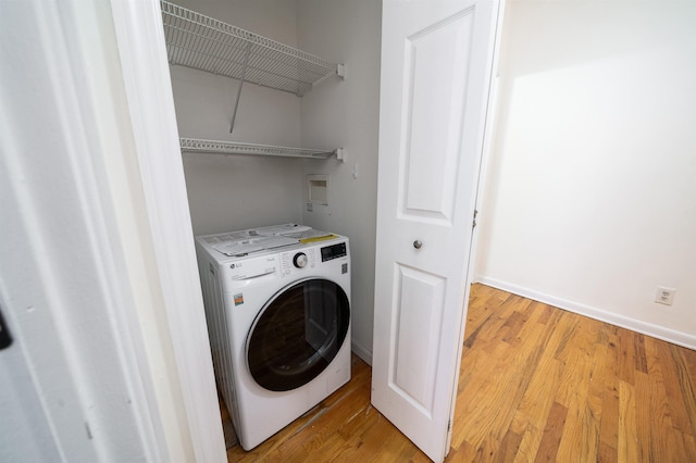 laundry area with washer / dryer and light hardwood / wood-style flooring