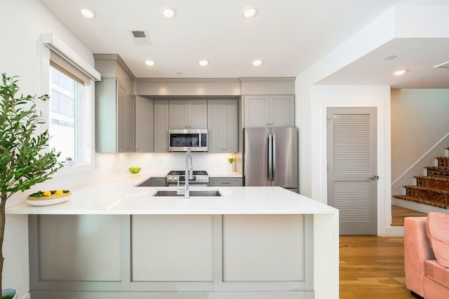 384 7th St Unit 5, Jersey City, NJ 07302 - kitchen featuring stainless steel appliances, gray cabinetry, a peninsula, light wood finished floors, and recessed lighting