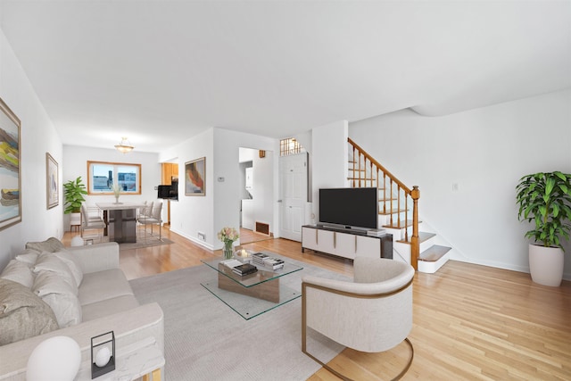 living room with light hardwood / wood-style flooring and a notable chandelier