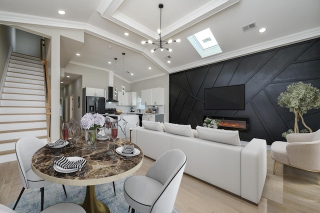 dining room featuring visible vents, a skylight, ornamental molding, stairs, and a decorative wall