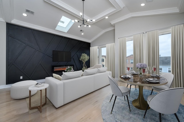 living area featuring visible vents, light wood-style flooring, a fireplace, ornamental molding, and lofted ceiling with skylight