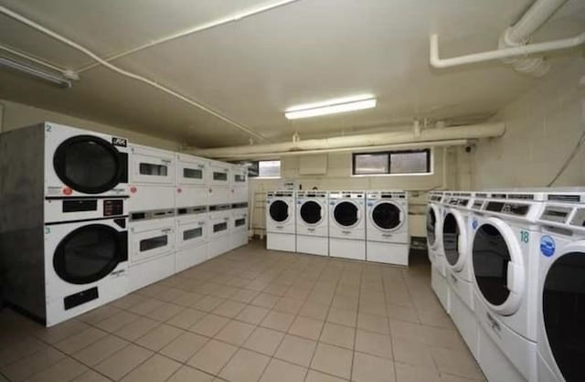 clothes washing area with washing machine and clothes dryer, stacked washer / dryer, and light tile patterned floors