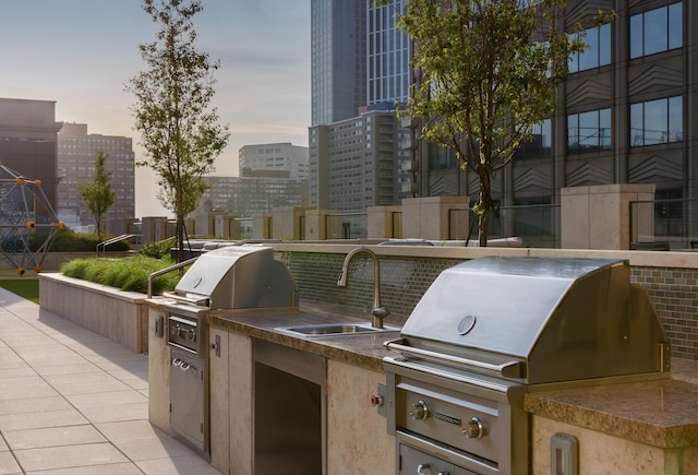 patio terrace at dusk with grilling area, sink, and an outdoor kitchen