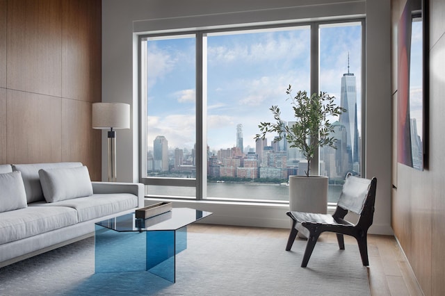 living room with a wealth of natural light, wooden walls, a water view, and light wood-type flooring