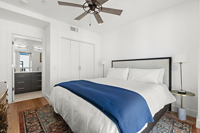 bedroom featuring a closet, a ceiling fan, visible vents, wood finished floors, and baseboards