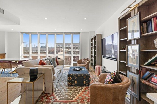living room with wood finished floors, visible vents, a wall of windows, and recessed lighting