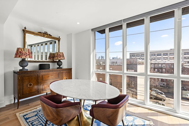 dining space featuring a city view, baseboards, recessed lighting, floor to ceiling windows, and wood finished floors