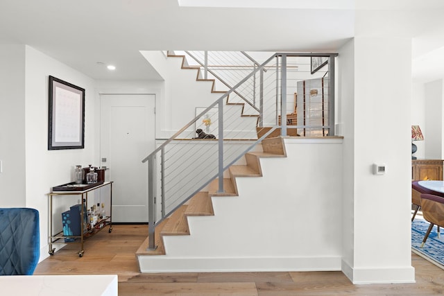 staircase featuring wood finished floors, baseboards, and recessed lighting