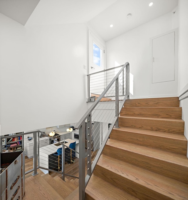 staircase with wood finished floors, vaulted ceiling, and recessed lighting