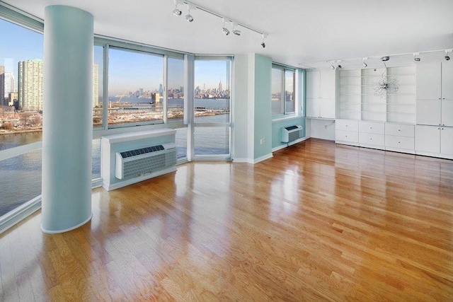 20 2nd St Unit 503, Jersey City, NJ 07302 - unfurnished living room featuring rail lighting, a wall mounted AC, wood finished floors, and a city view