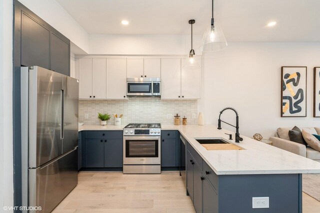 425 3rd St Unit 219, Jersey City, NJ 07302 - kitchen with stainless steel appliances, a sink, a peninsula, light wood-type flooring, and backsplash