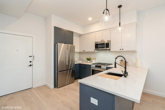 425 3rd St Unit 219, Jersey City, NJ 07302 - kitchen with appliances with stainless steel finishes, a sink, a peninsula, light stone counters, and light wood-style floors