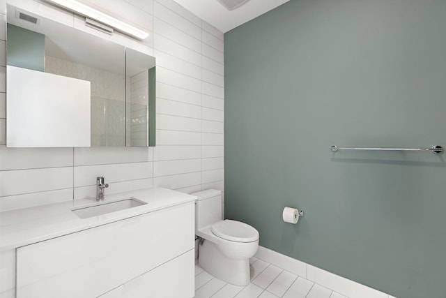 bathroom with toilet, visible vents, baseboards, tile walls, and tile patterned floors