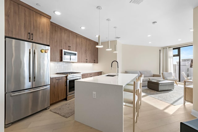 kitchen featuring light countertops, appliances with stainless steel finishes, a sink, and pendant lighting