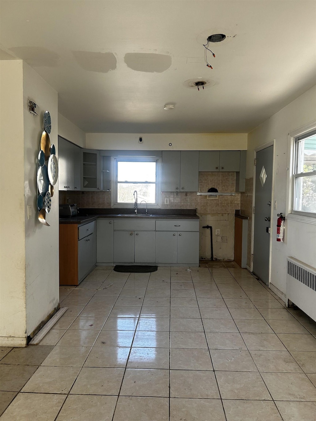 kitchen with dark countertops, radiator heating unit, light tile patterned floors, and a sink