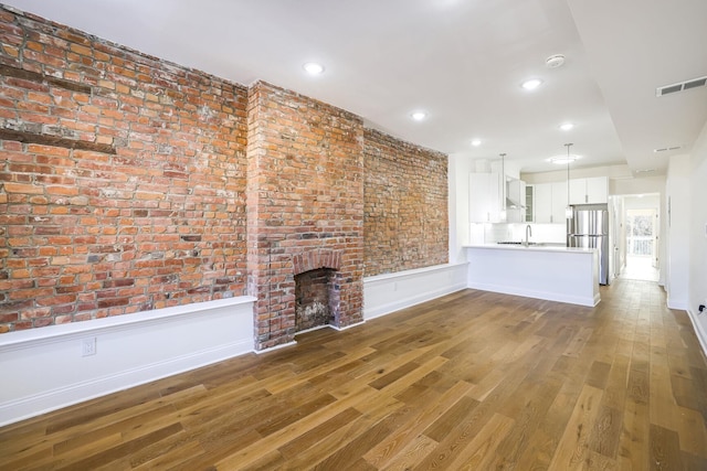 unfurnished living room with hardwood / wood-style floors, sink, and a fireplace