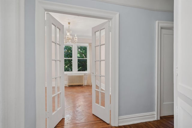 hallway with french doors, dark parquet flooring, radiator, ornamental molding, and a notable chandelier