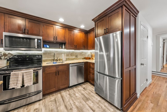607 1st St Unit 1, Hoboken, NJ 07030 - kitchen with appliances with stainless steel finishes, a sink, light wood-type flooring, decorative backsplash, and light stone countertops