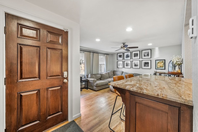607 1st St Unit 1, Hoboken, NJ 07030 - kitchen featuring a ceiling fan, light wood-style floors, recessed lighting, light stone countertops, and a breakfast bar