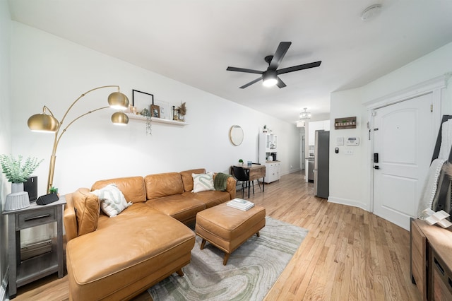 living room featuring light wood-style flooring, a ceiling fan, and baseboards